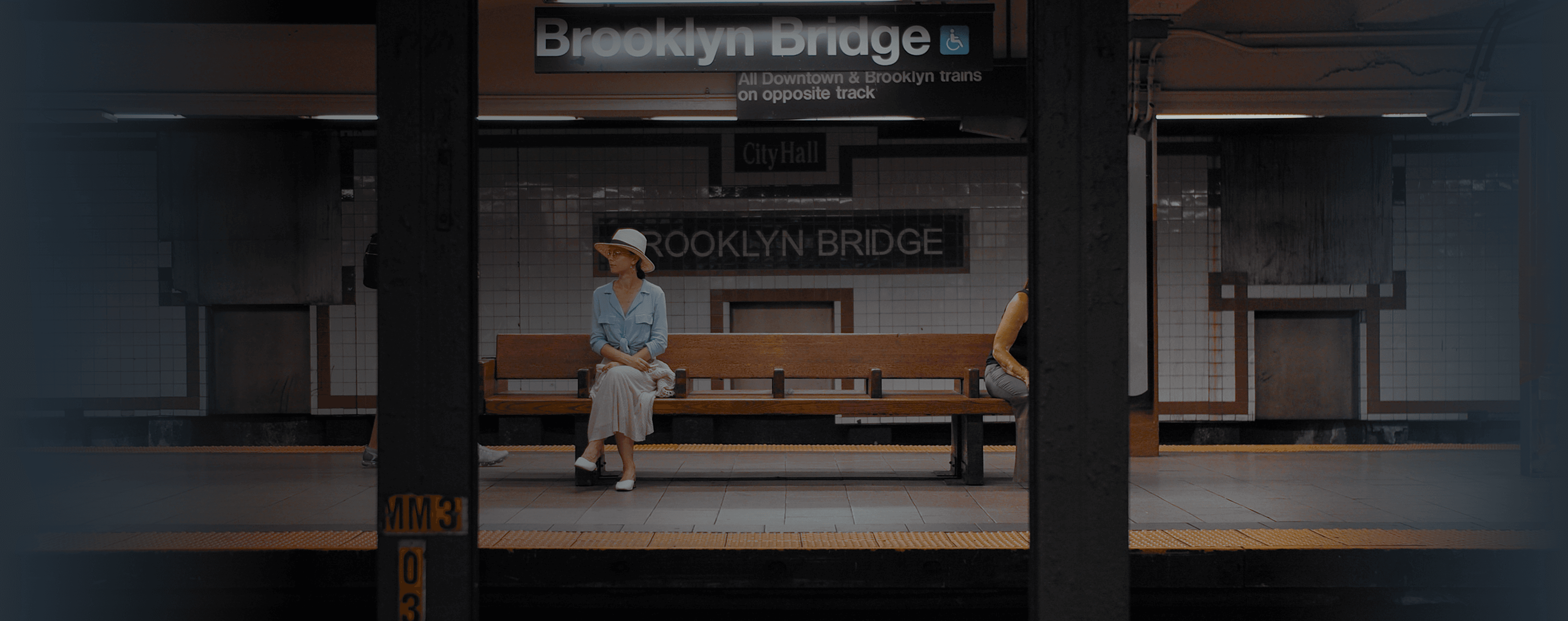 Una mujer se sienta en un banco en una estación de metro.